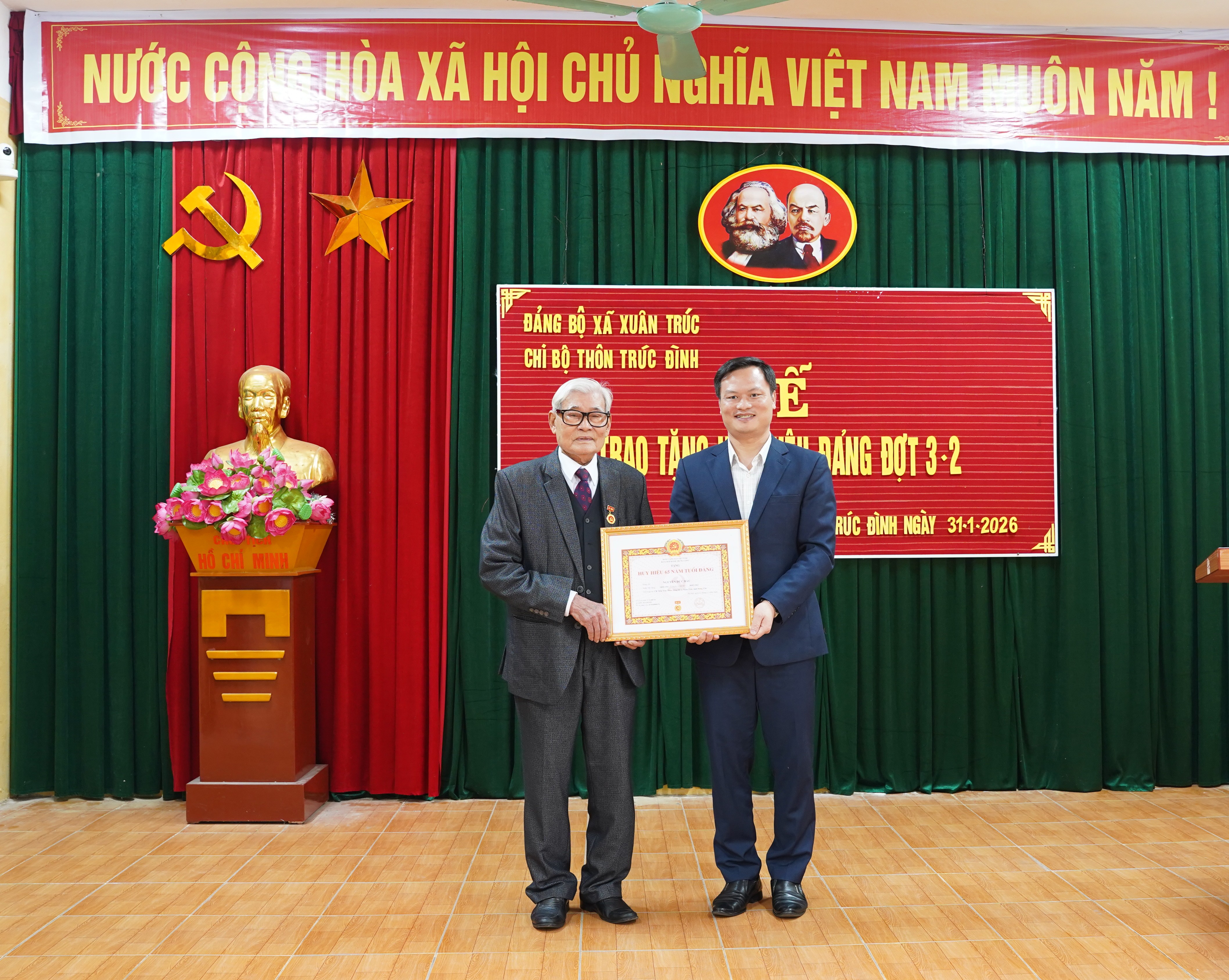 Đồng chí Phạm Khắc Huân, Phó Bí thư Đảng ủy, Chủ tịch UBND xã dự và trao Huy hiệu 65 năm tuổi Đảng cho đảng viên Nguyễn Đức Báu, sinh hoạt tại Chi bộ thôn Trúc Đình.